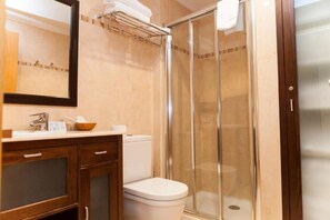 A bathroom with a toilet, a sink, a mirror, and a glass-enclosed shower. - Hotel Sercotel Tres Luces (Vigo)