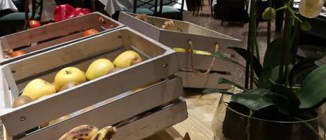 A buffet table with fruit and a potted orchid.
