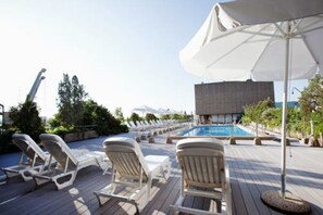 Una piscina al aire libre de temporada, sombrillas