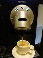 A Nespresso coffee machine dispensing coffee into a cup.