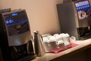 A coffee station with a coffee machine and a kettle, and a display of disposable cups. - Hotel Goya (Zaragoza)