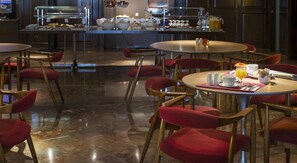 A hotel dining area with round tables and red upholstered chairs. - Hotel Goya (Zaragoza)