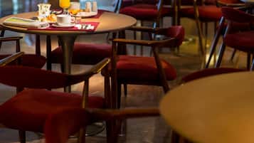 A dining area with round tables and red upholstered chairs.