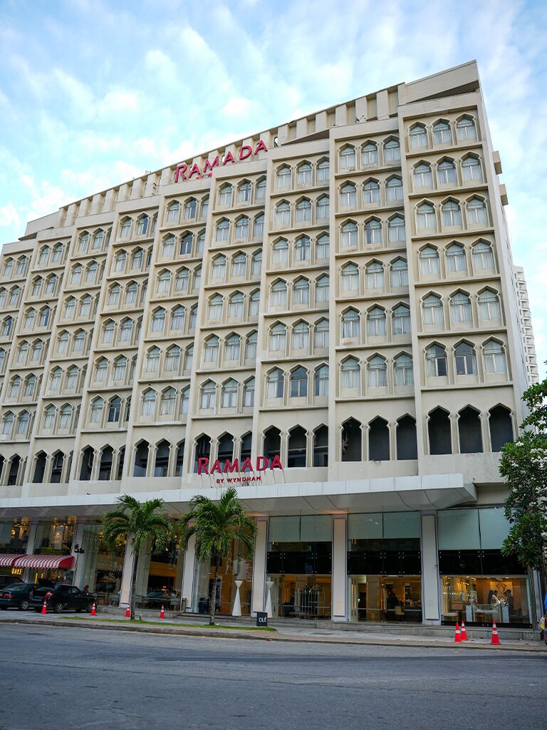 Un hotel de varios pisos con un llamativo letrero de 'RAMADA' en la fachada.