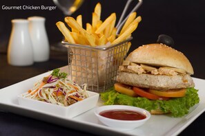 Um hambúrguer de frango gourmet com batatas fritas e uma salada.