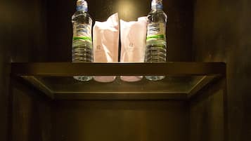 A hotel room with a minibar containing bottled water, a tissue, and a small box.