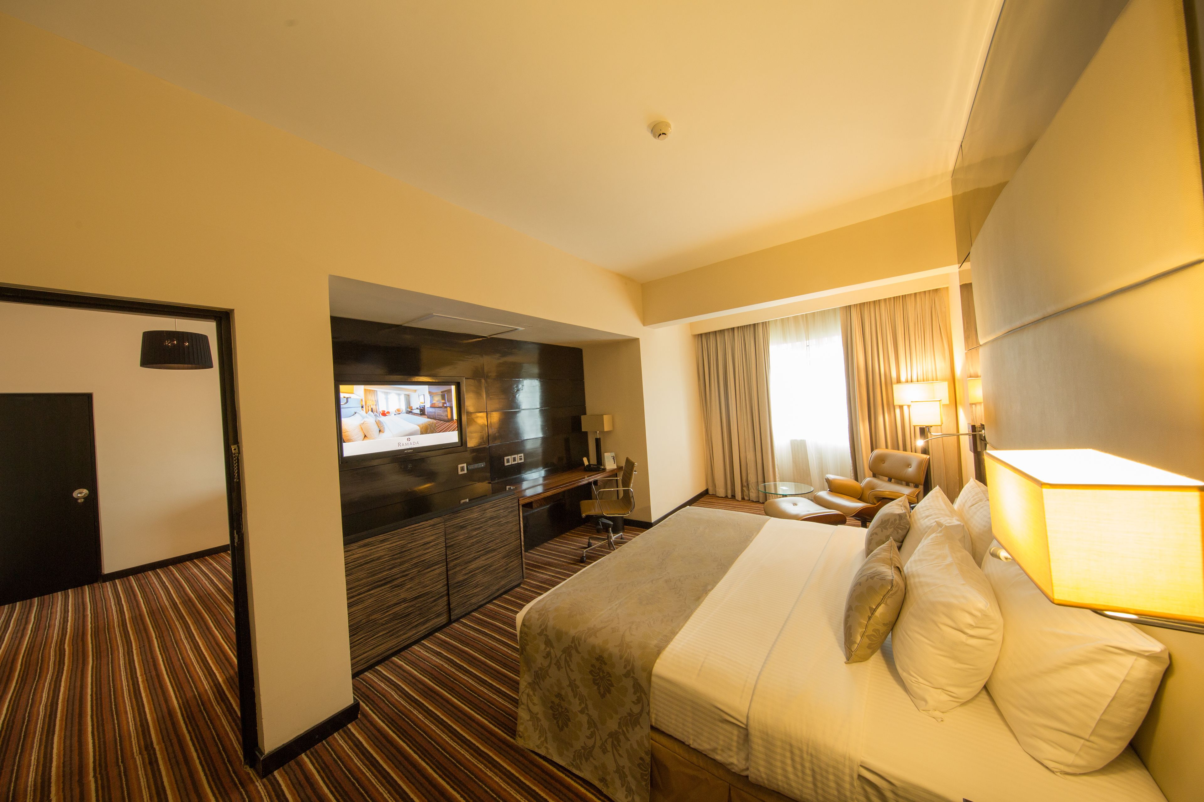 A hotel room with a bed, a desk, a television, and a bathroom.