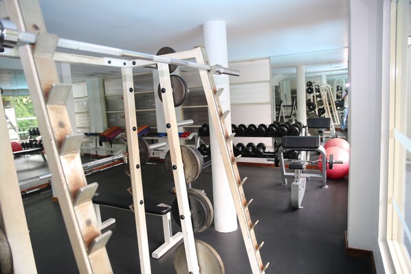 A gym with weightlifting equipment, mirrors, and exercise balls.