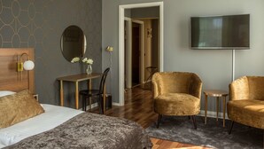 A hotel room with a bed, two armchairs, a small table, a mirror, and a TV. - Hotell Boras, BW Signature Collection (Borås)