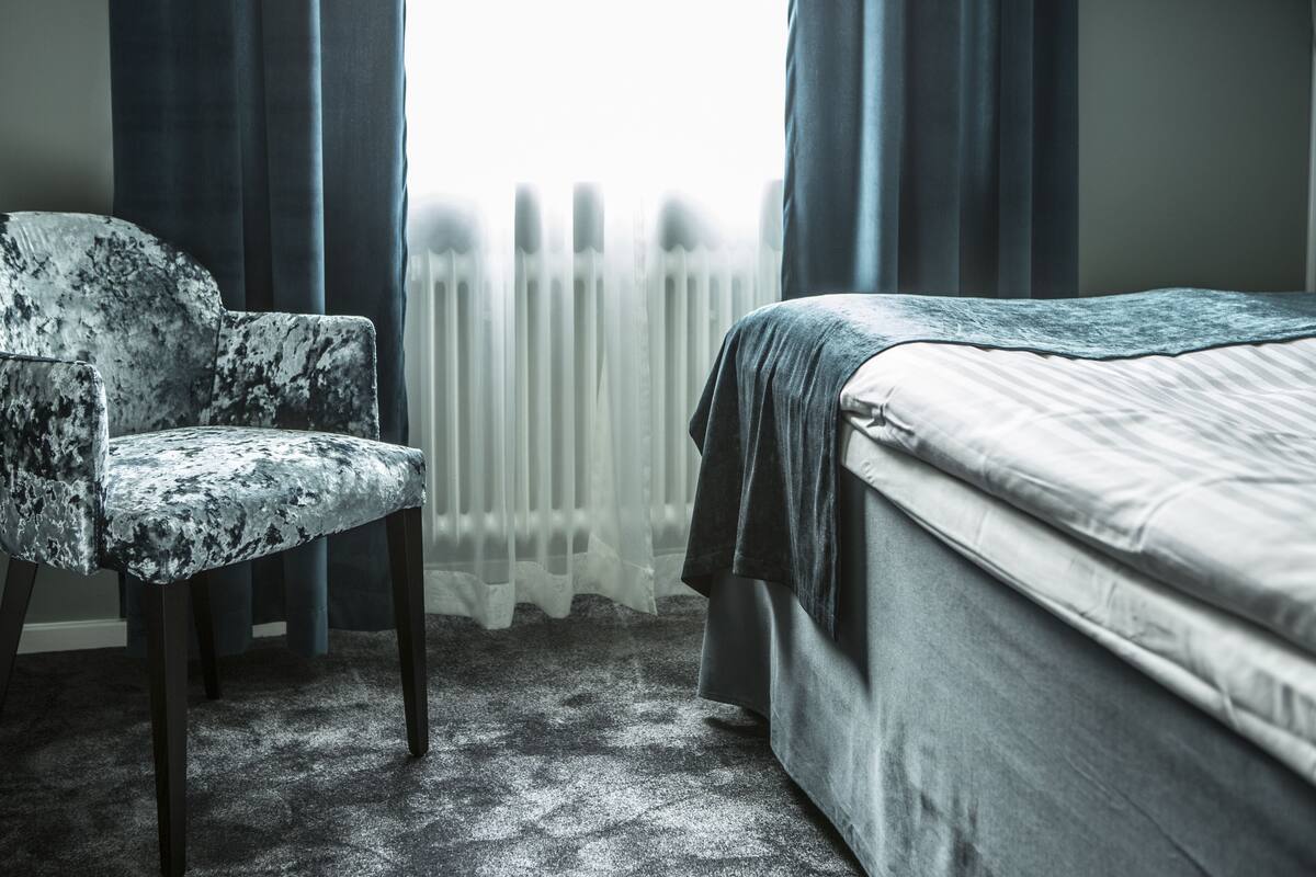 A bedroom with a bed, a chair, and a radiator.