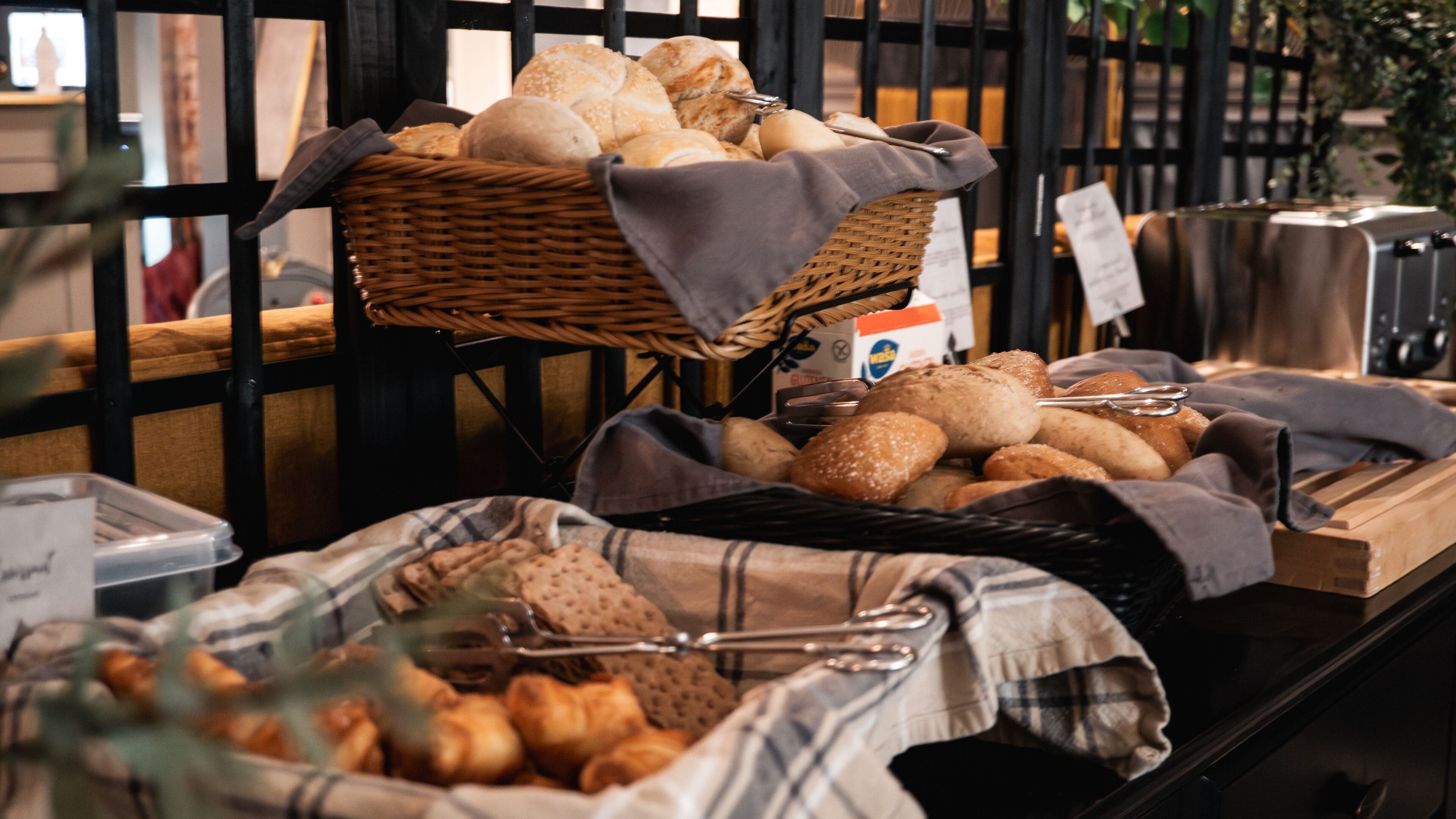 A buffet with various breads and pastries displayed in baskets and on a counter.