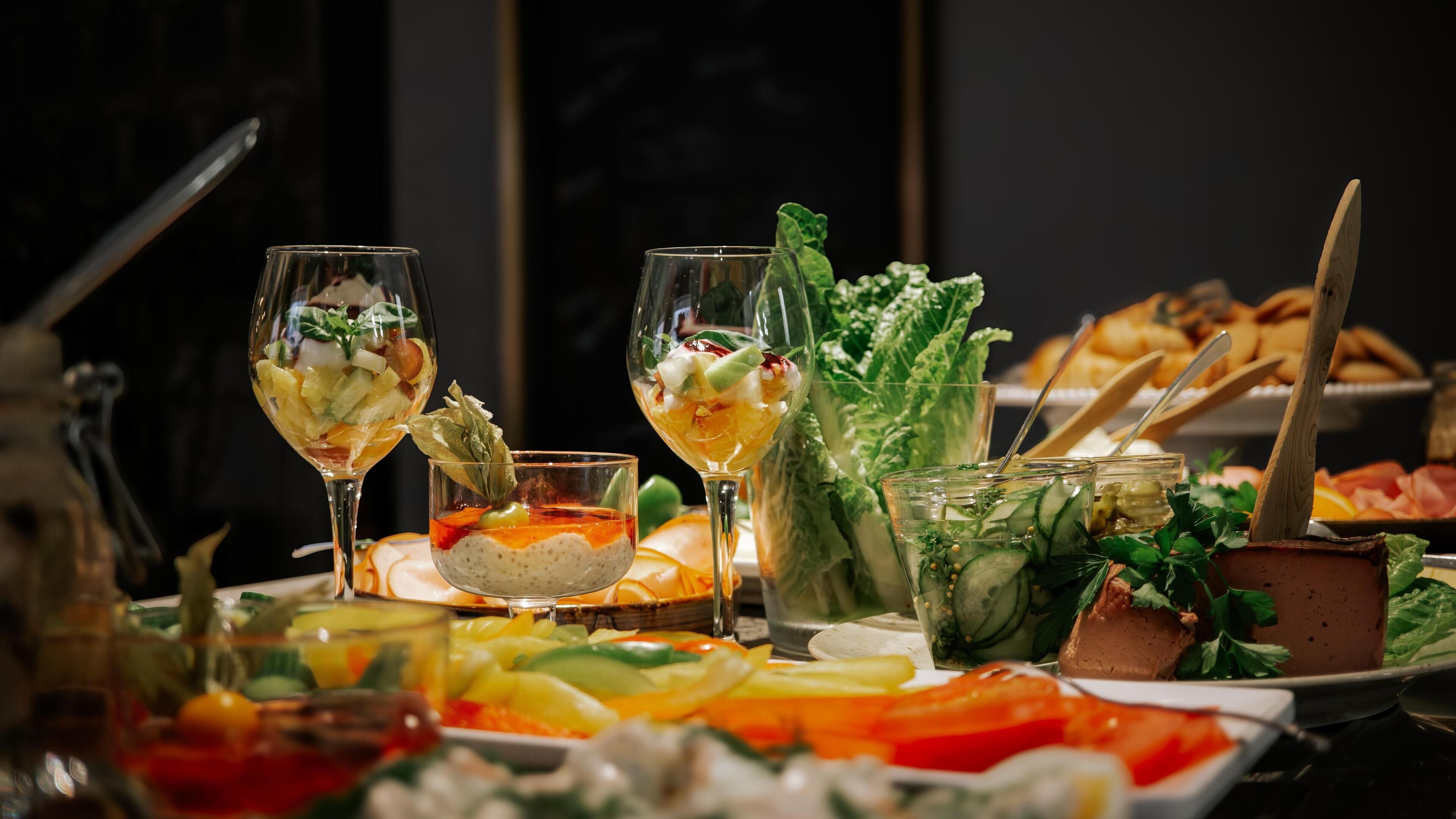 A buffet with various dishes, including a variety of salads, fruits, and a selection of cheeses.
