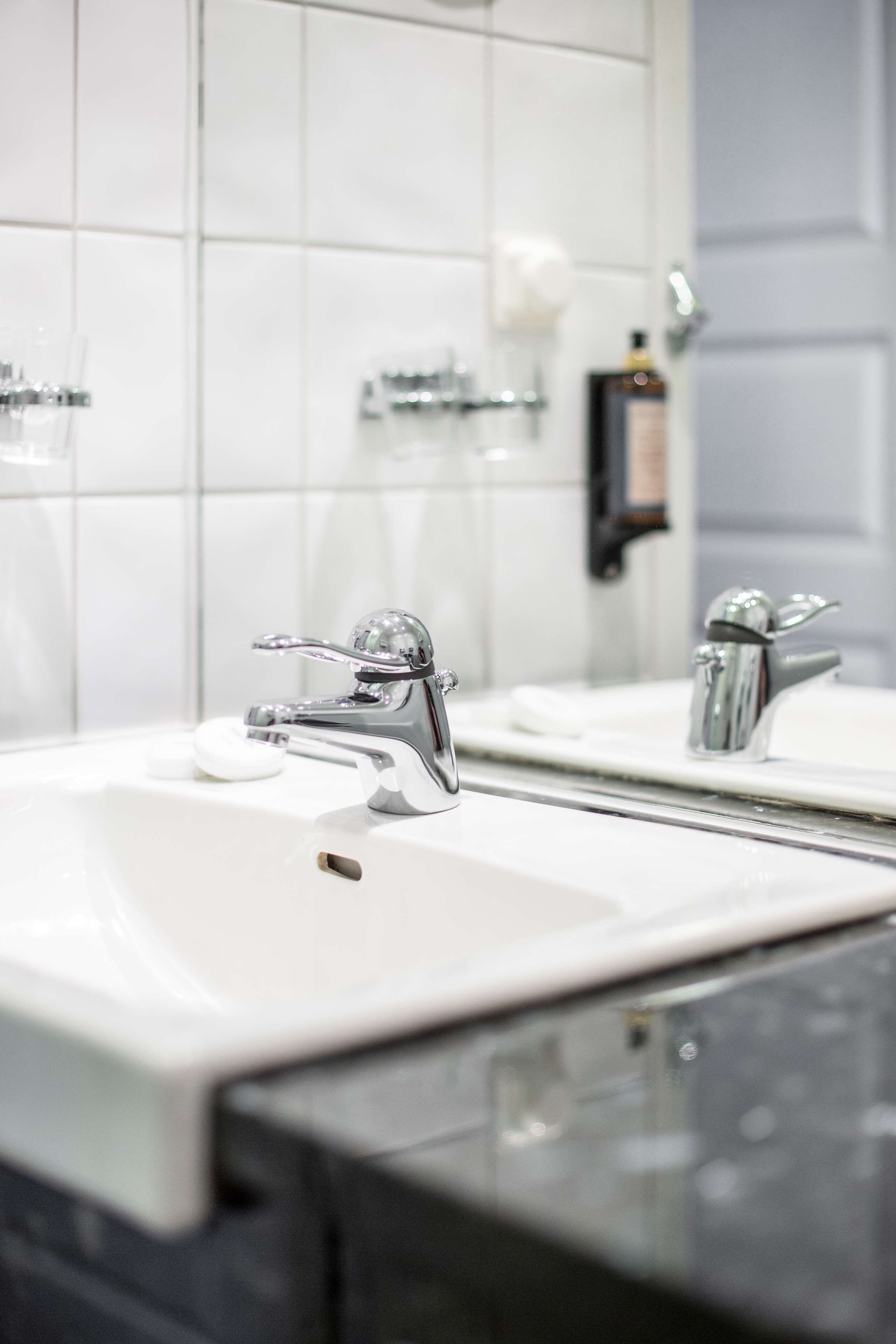 A bathroom with two sinks, a mirror, and a soap dispenser.