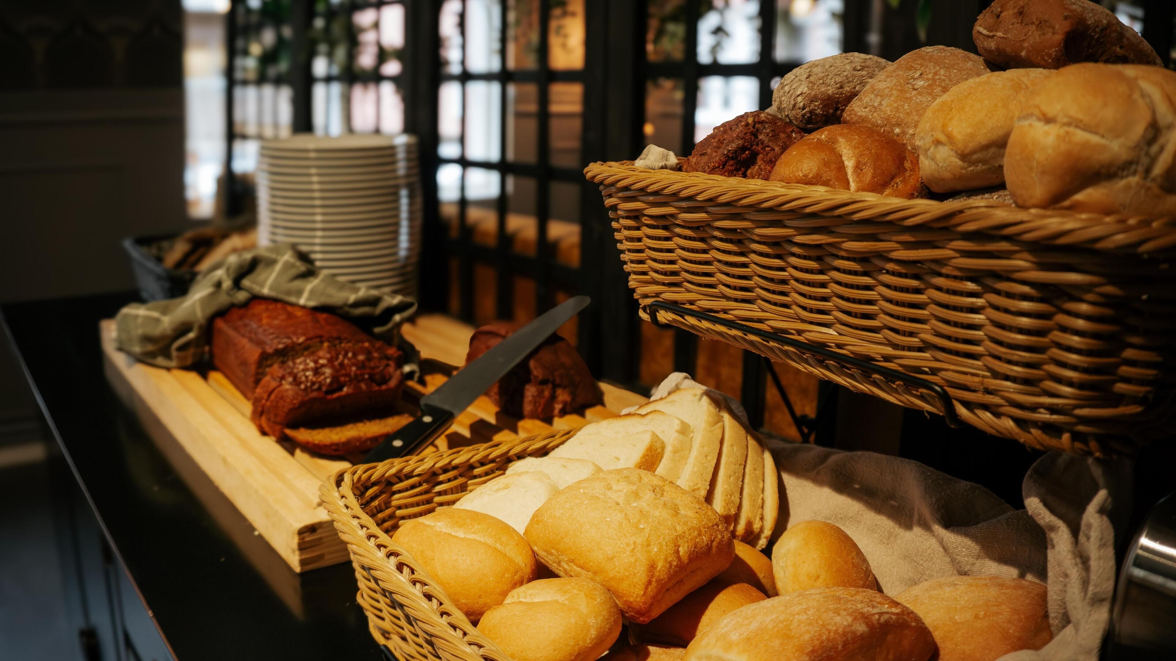 A buffet with various breads and pastries displayed in wicker baskets.