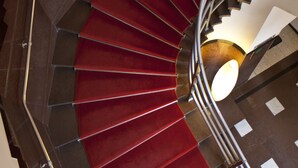A spiral staircase with red carpeted steps and a metal railing. - Hotell Boras, BW Signature Collection (Borås)