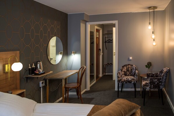 A hotel room with a bed, a desk, a chair, a mirror, and a hanging light fixture. - Hotell Boras, BW Signature Collection (Borås)