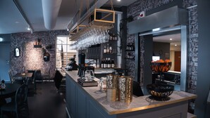 A modern bar area with a counter, hanging glasses, and a variety of bottles. - Hotell Boras, BW Signature Collection (Borås)