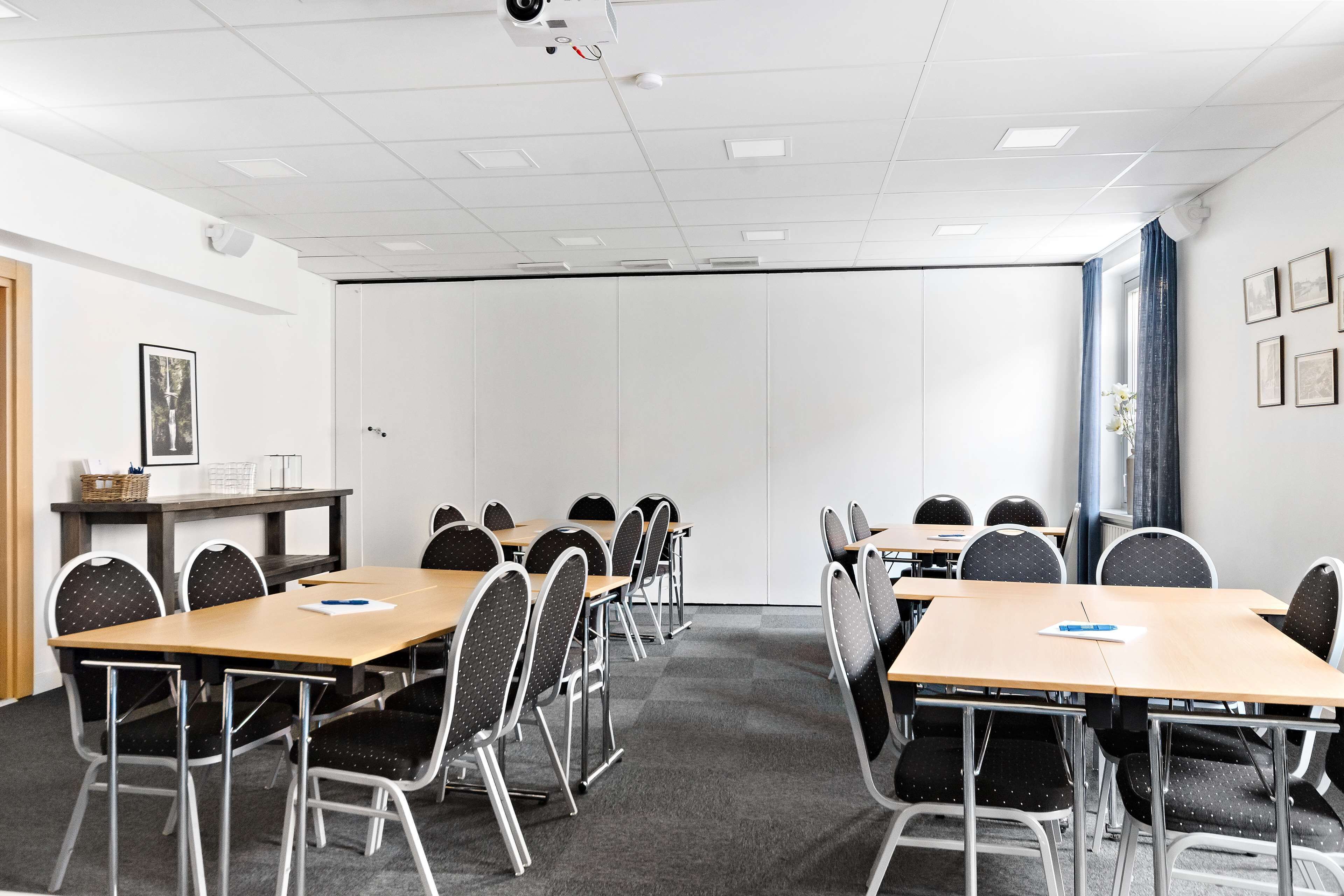 A conference room with tables and chairs, white walls, and a door.