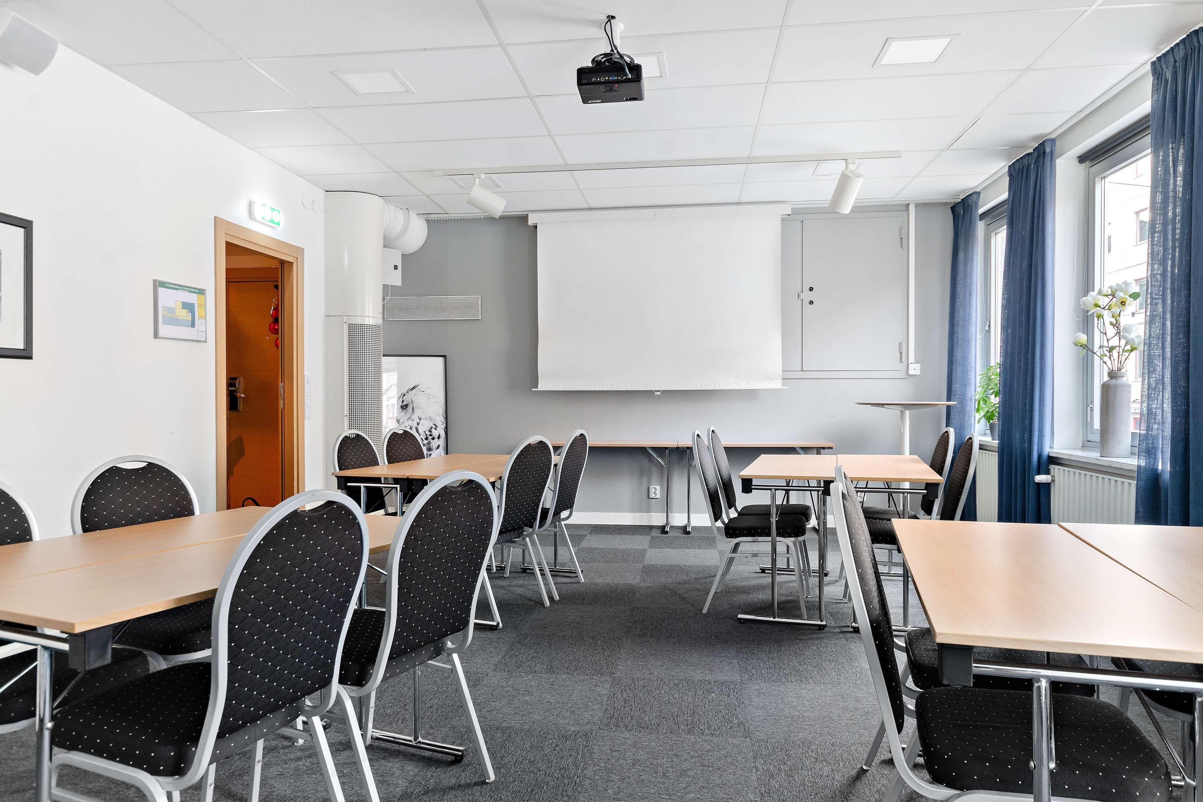 Ett konferensrum med bord och stolar, en projektor och en whiteboard.