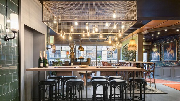 A bar area with multiple stools, a long counter, and hanging light fixtures. - Best Western Plaza Hotel (Eskilstuna)
