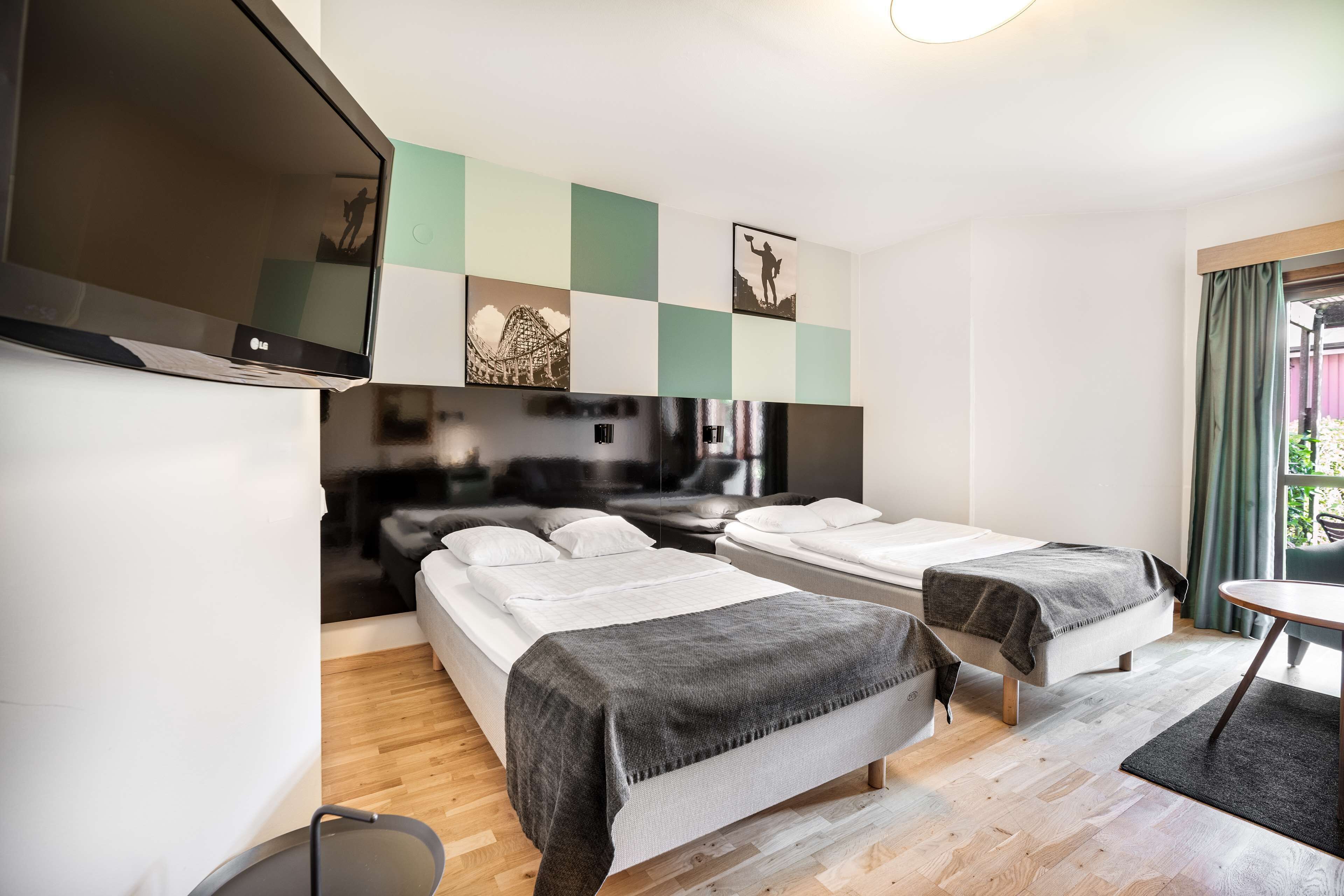 A hotel room with two beds, a TV mounted on the wall, and a small table.