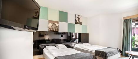 A hotel room with two beds, a TV mounted on the wall, and a small table.
