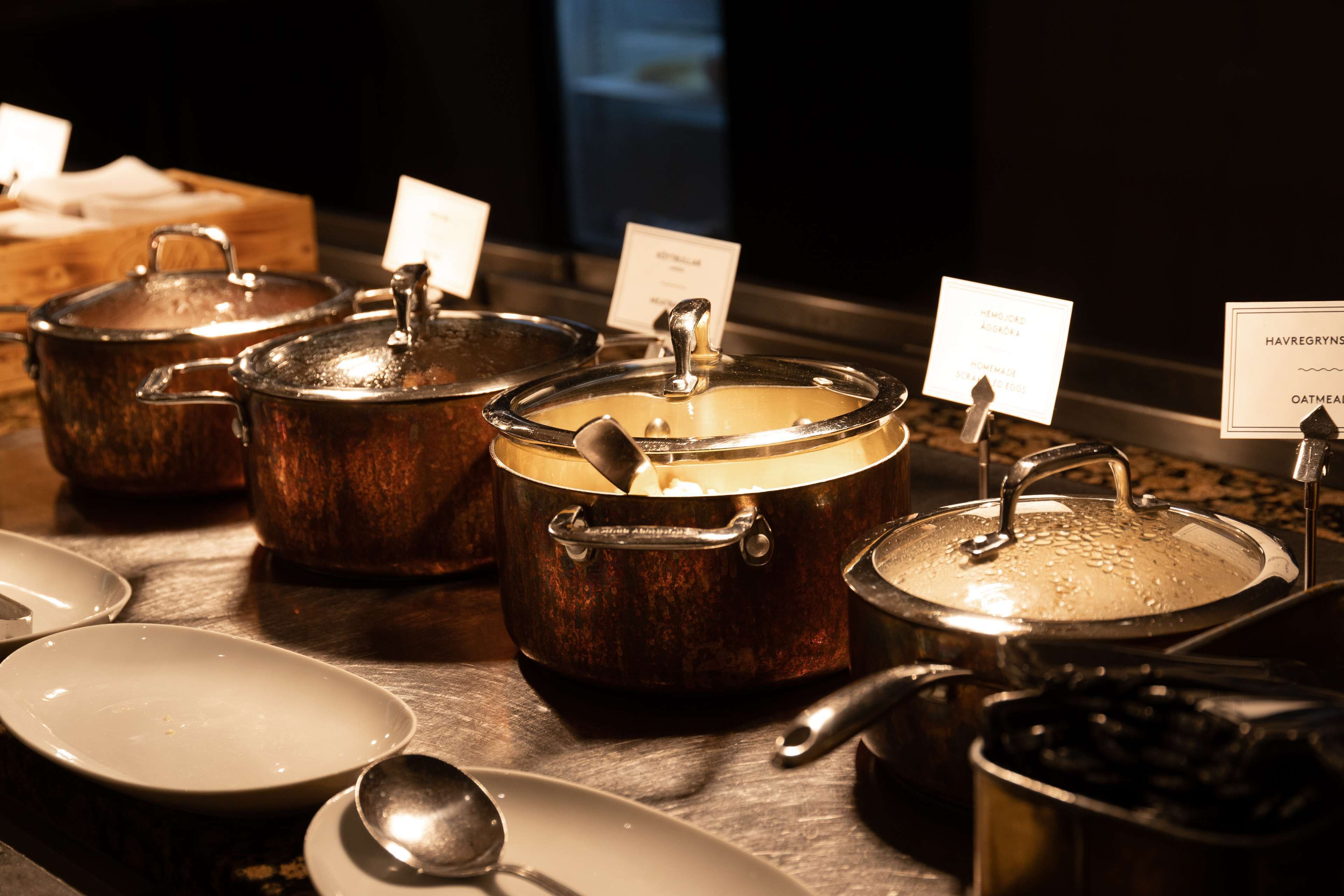 Un espace buffet avec plusieurs récipients contenant différents plats, chacun étant étiqueté avec le nom du plat.