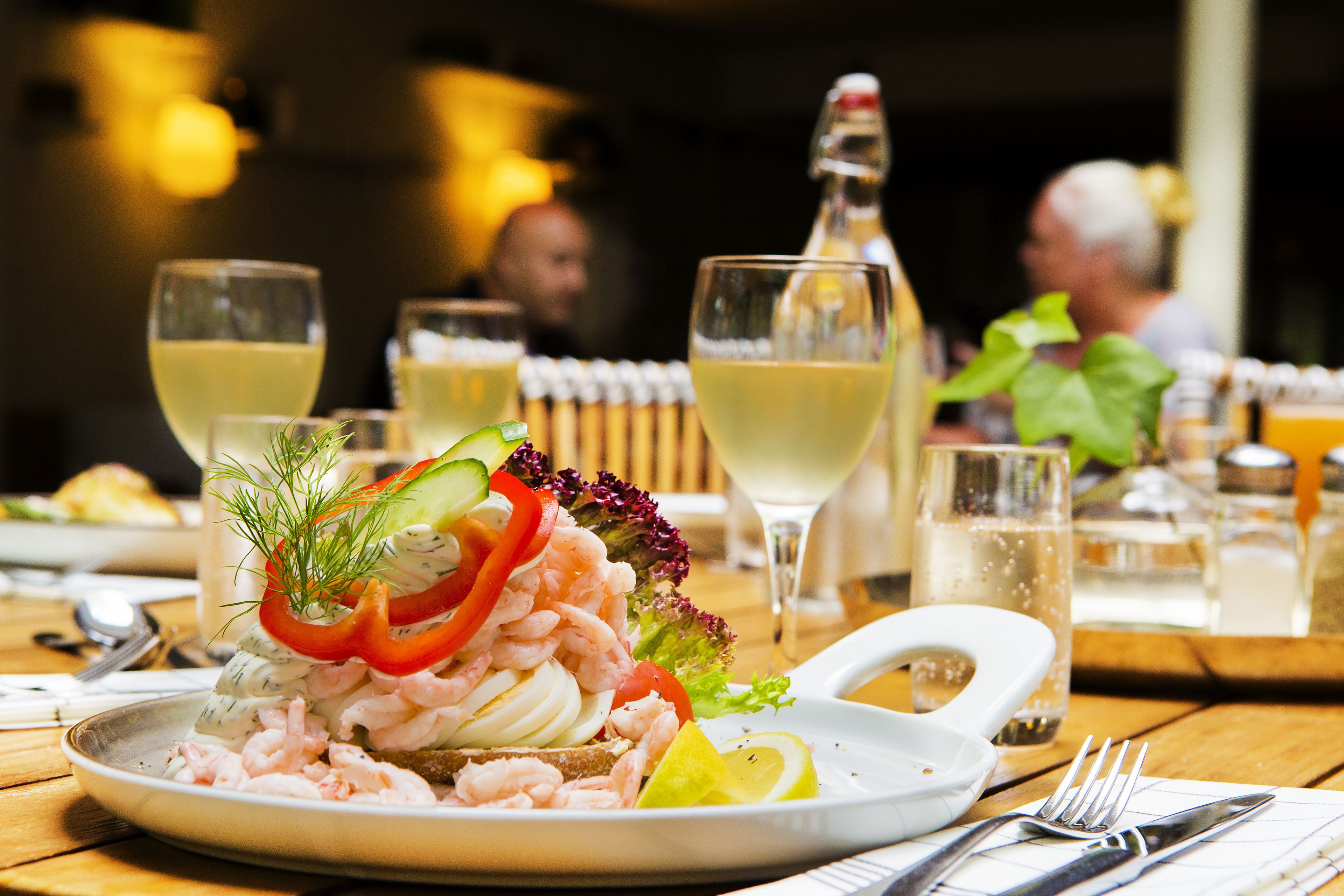 A seafood dish on a plate with a lemon wedge, garnished with dill and red pepper.