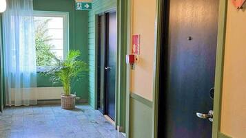 A hotel corridor with a door marked 'Room 101,' a potted plant, and a directional sign.