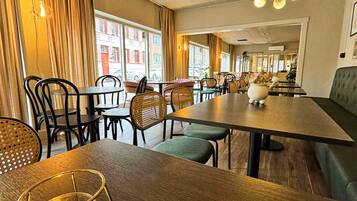 L’intérieur d’un restaurant avec des tables en bois, des chaises en osier et une bougie posée sur une table.