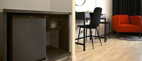 Un espacio habitable compacto con kitchenette, una zona de comedor con mesa y sillas, y un sofá rojo.
