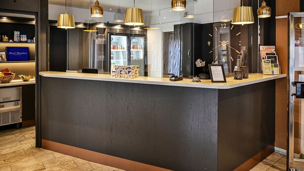 Un mostrador de recepción de diseño moderno, con una vitrina de cristal, un cartel de bienvenida enmarcado y un reloj digital.