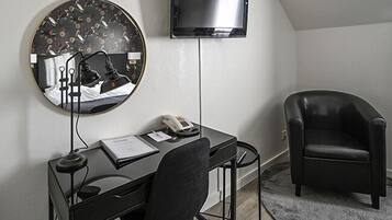 A modern room with a desk, chair, and a round mirror with a floral pattern.