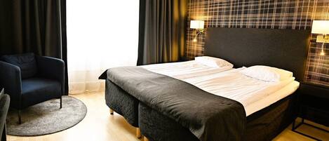Una habitación de hotel con una cama, una silla y una mesita de noche con lámparas.