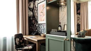 A room with a desk, chair, and a cabinet with a wine bottle and glasses.