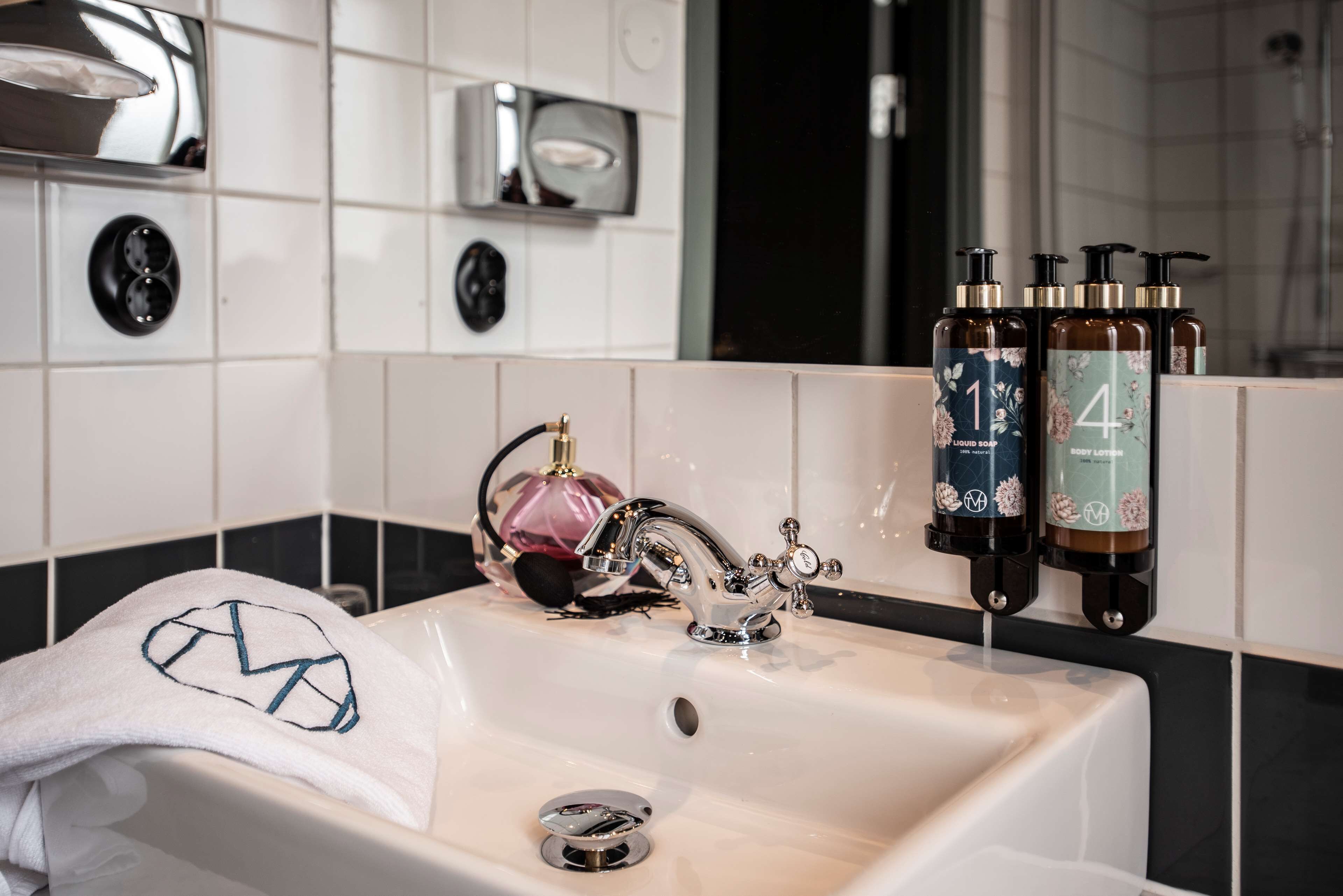 A bathroom with a sink, a towel, and two bottles of liquid soap.