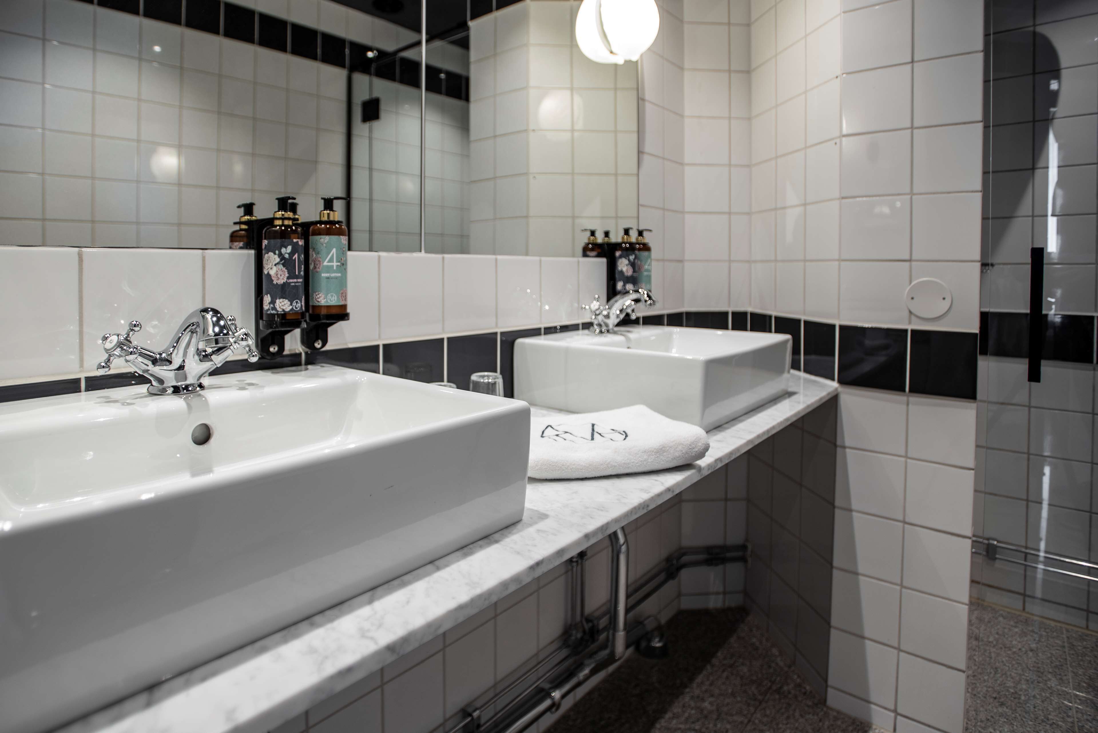 A modern bathroom with two sinks, a large mirror, and a shower area.