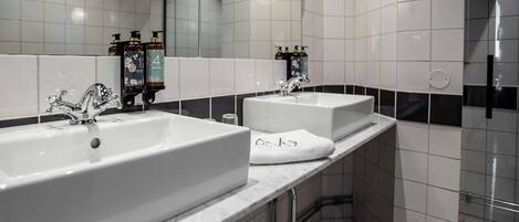 A modern bathroom with two sinks, a large mirror, and a shower area.