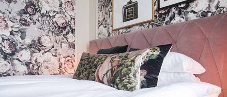 A neatly made bed with floral-patterned pillows and a tufted headboard.