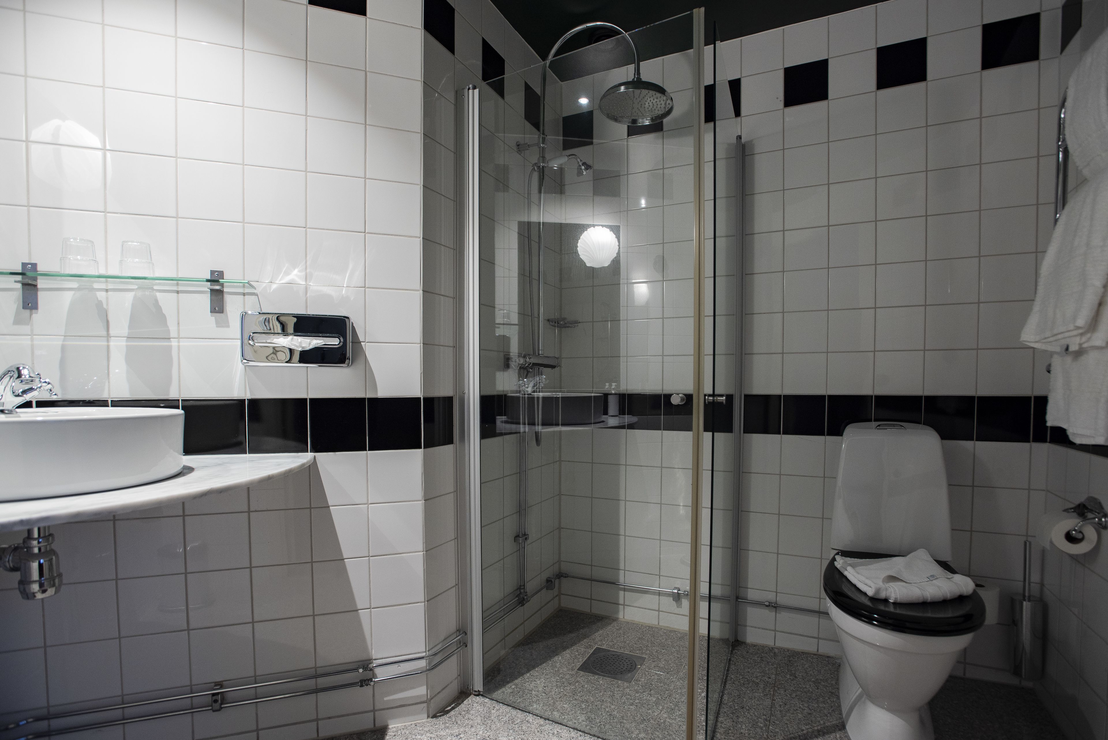 A modern bathroom with a glass-enclosed shower, a white sink, and a toilet.