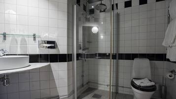 A modern bathroom with a glass-enclosed shower, a white sink, and a toilet.