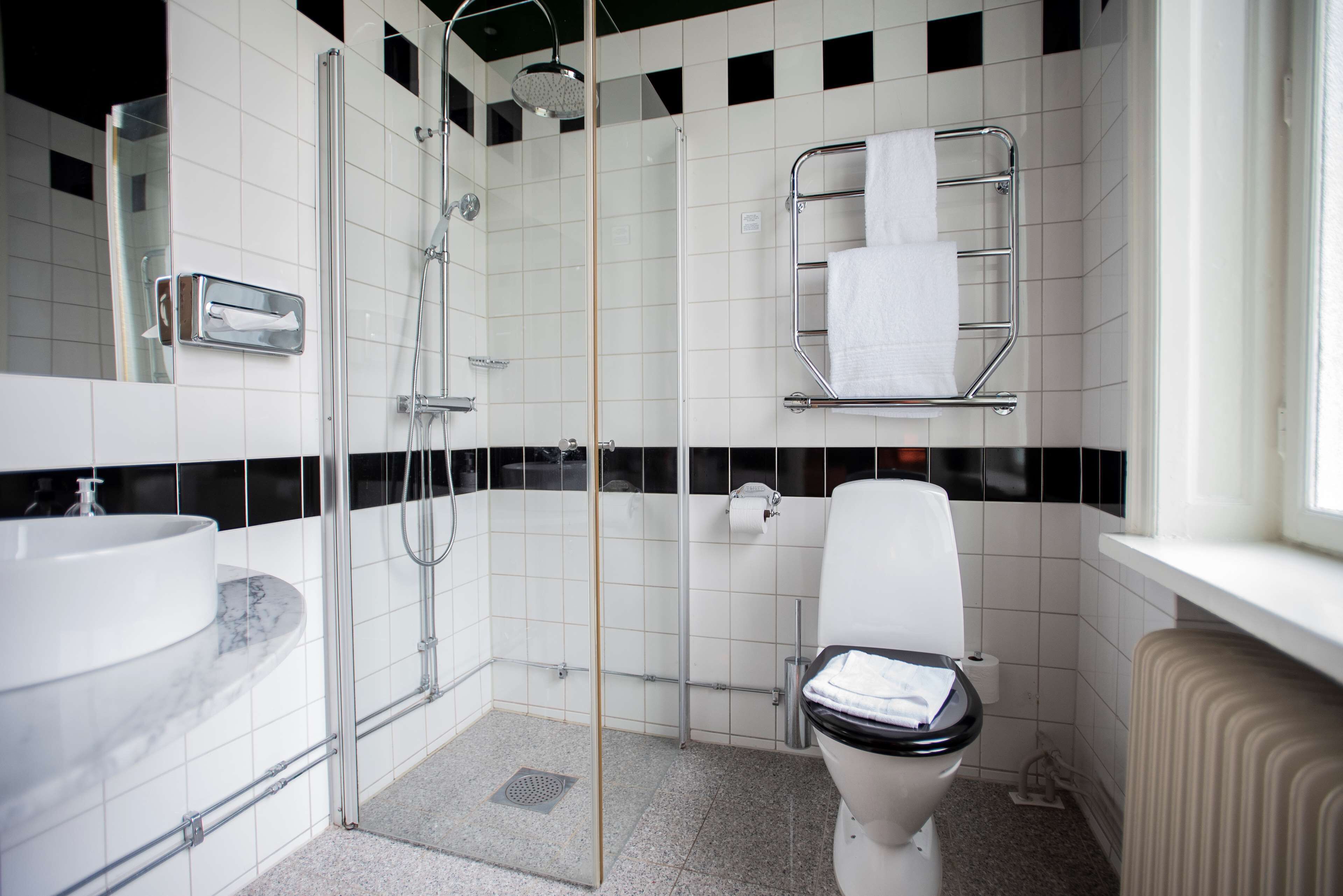 A modern bathroom with a glass-enclosed shower, a white toilet, and a marble sink.