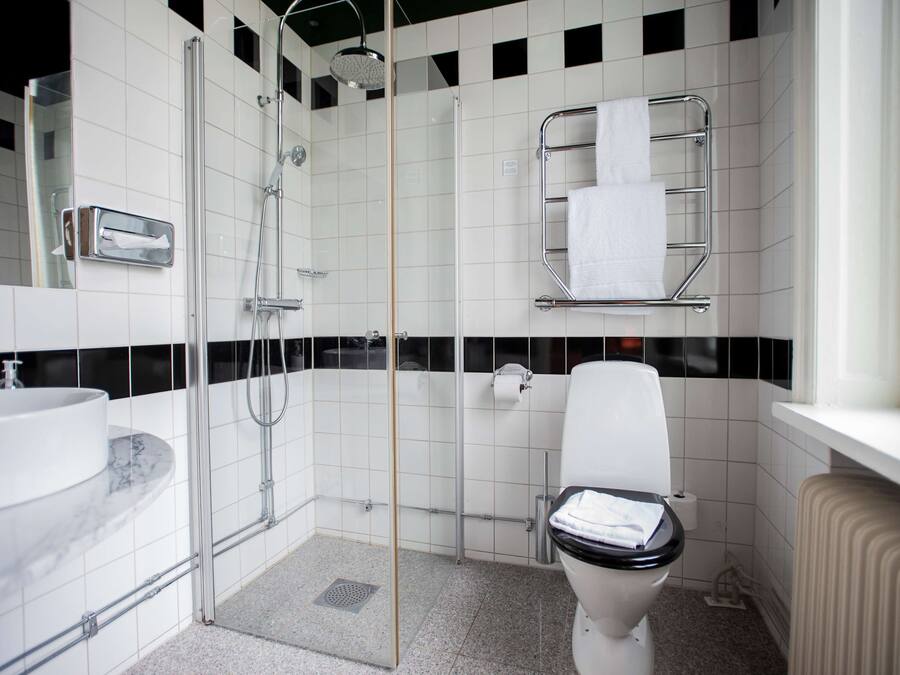 A modern bathroom with a glass-enclosed shower, a white toilet, and a marble sink.