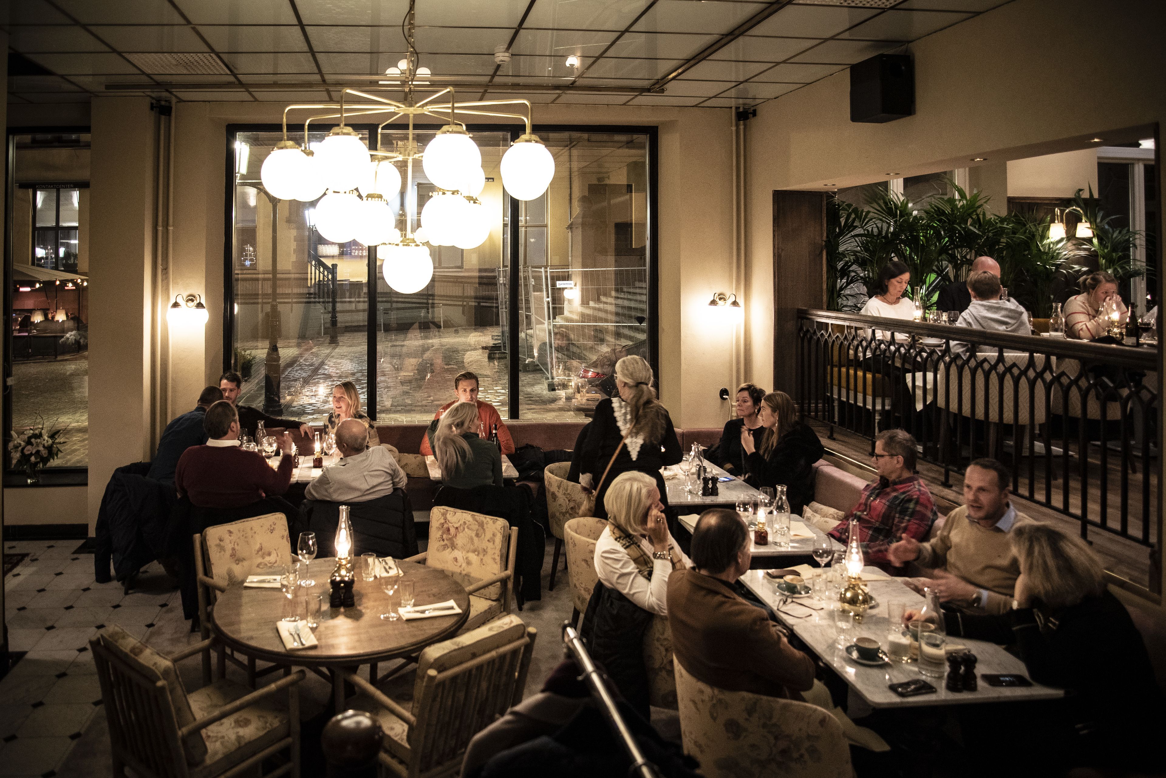Un restaurante con mesas redondas, sillas y lámparas colgantes.