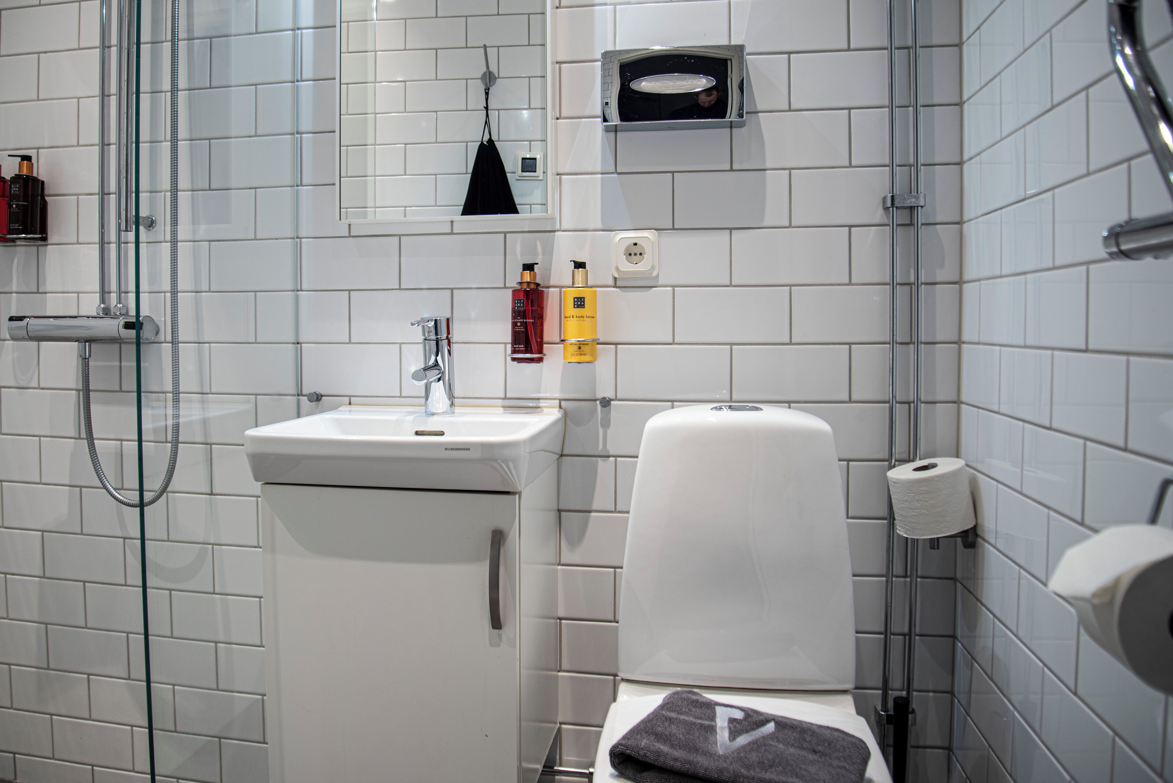 Een moderne badkamer met een douchecabine van glas, een wit wastafelmeubel en een toilet.