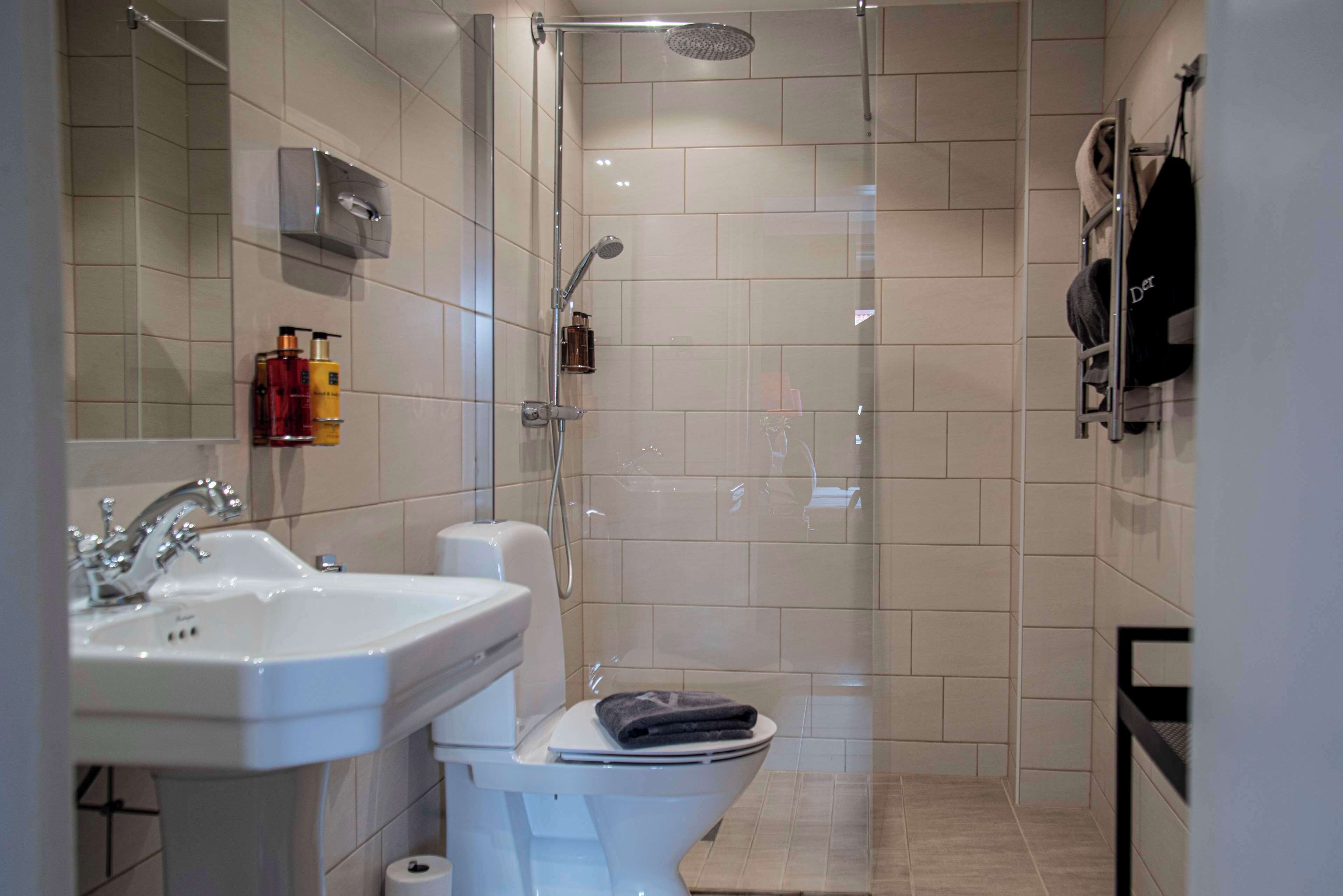 A modern bathroom with a shower, toilet, sink, and towel rack.