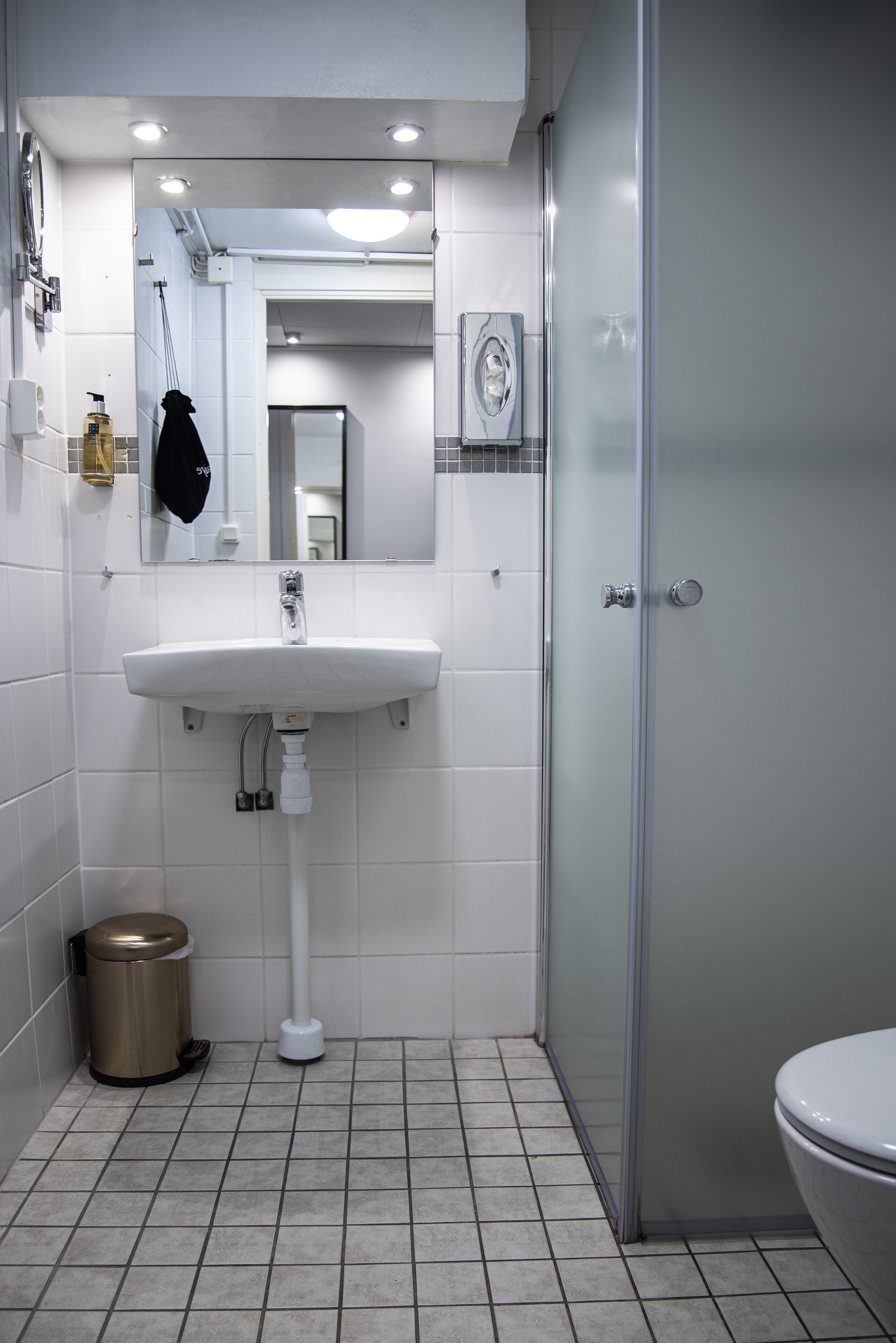 Un baño con lavamanos, espejo y retrete blancos.