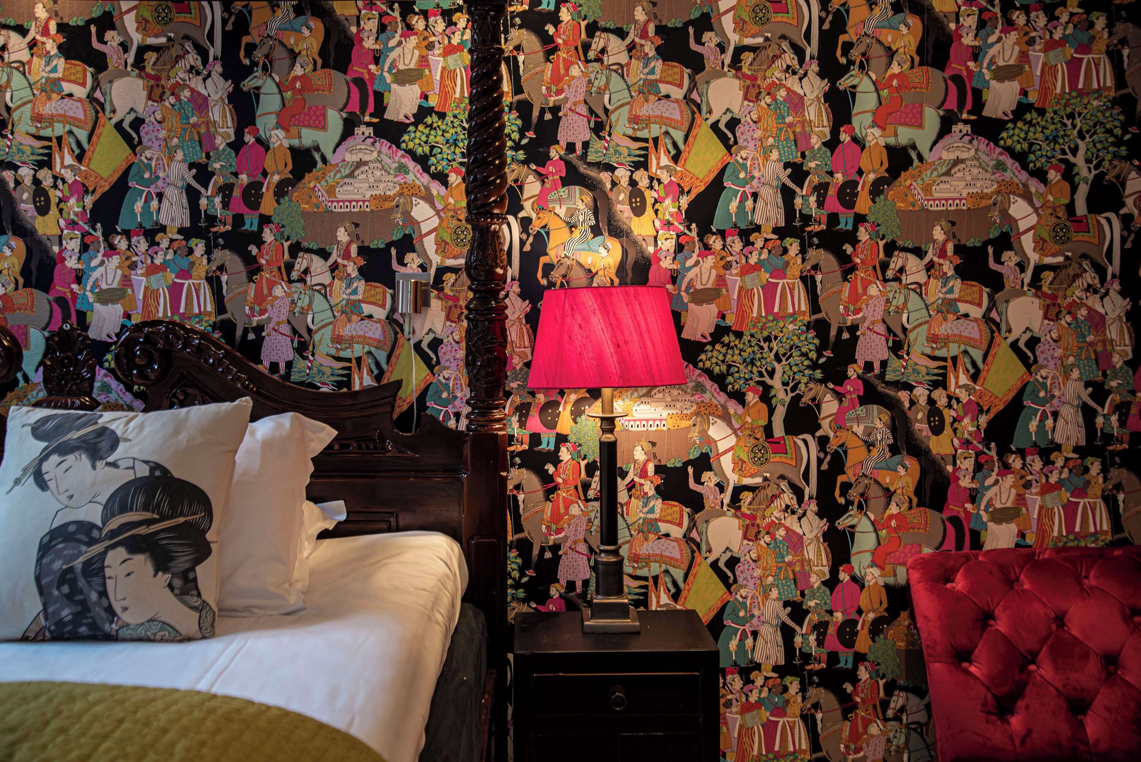 A bedroom with a traditional Japanese-style bed, a red lamp, and a wall covered with colorful artwork.