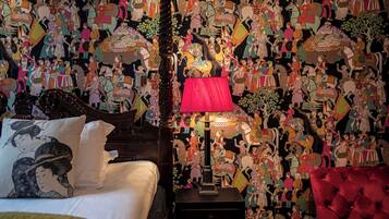 A bedroom with a traditional Japanese-style bed, a red lamp, and a wall covered with colorful artwork.