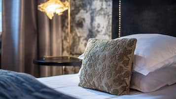 A neatly made bed with a patterned pillow and a bedside lamp.